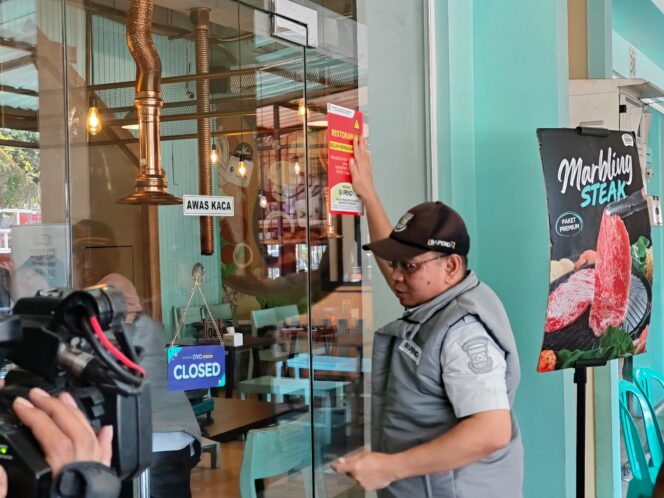 
 Kepala Bidang Pengawasan, Pemeriksaan dan Penagihan (Wasdal) Bapenda Kabupaten Tangerang Fahmi Faisuri saat menempel Sticker Tunggakan pada Objek Usaha Wajib Pajak. Foto: Ist