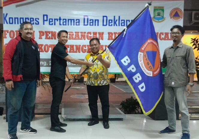 
 Kepala Pelaksana BPBD Kota Tangerang Mahdiar Didampingi Ketua Sidang Kongres Pertama FPRB Andri S.Permana menyerahkan Pataka kepada Ketua FPRB Kota Tangerang terpilih, H.Supiani. Foto: TangerangPos 